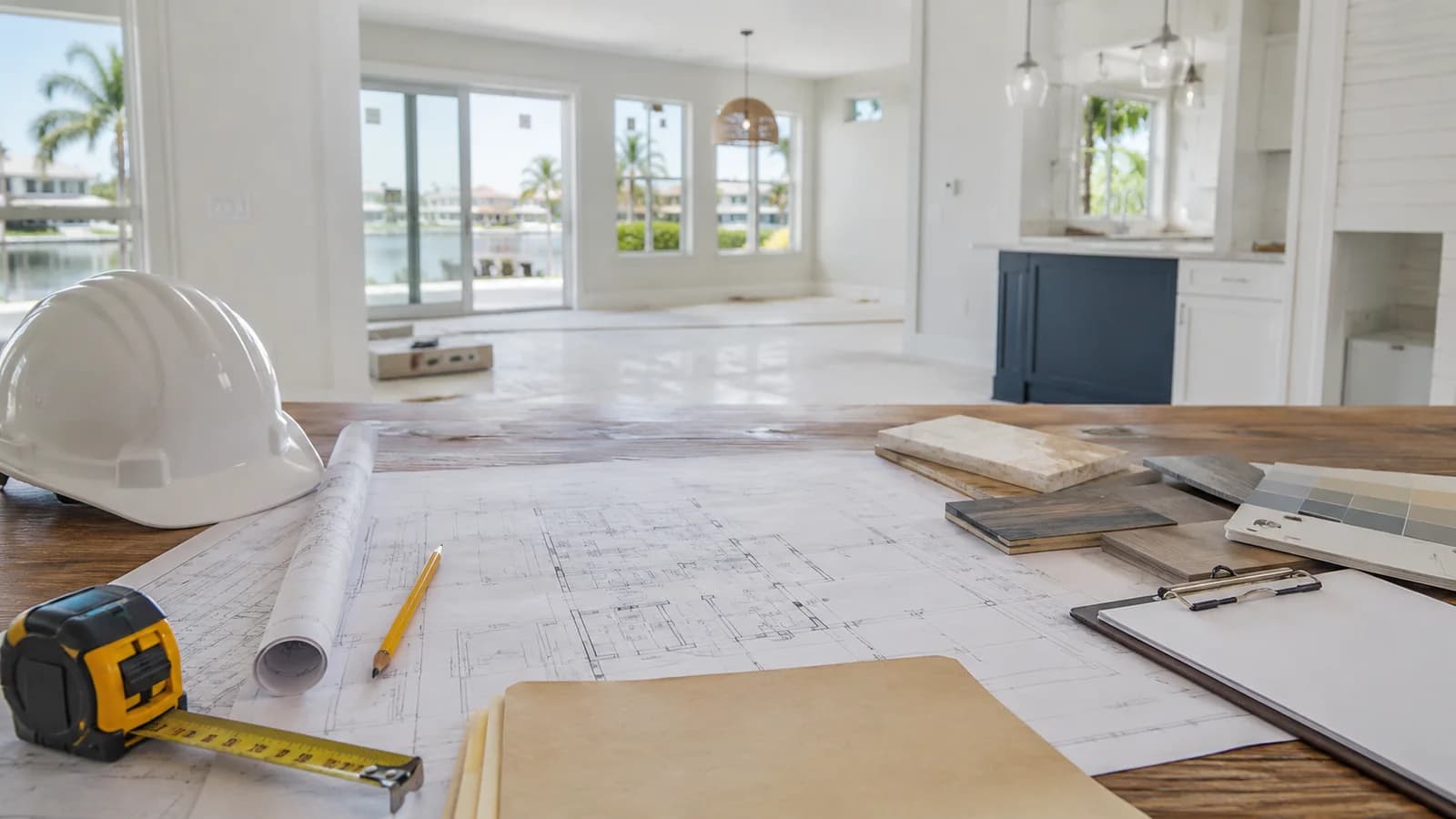 Construction plans, hard hat, measuring tape, and material samples inside a bright coastal Florida home